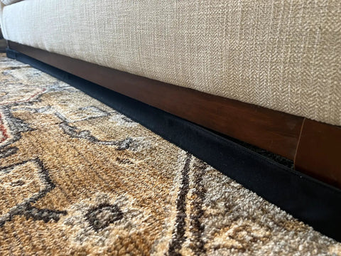 Adjustable Under Couch Gap Shield Blocking Toys Dust And Remotes From Snaking Under Sofas Beds Or Cabinets With Hassle Free Snap Fit And Tough Flexible Core beside beige couch and patterned rug.