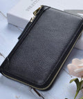 Women's RFID Blocking Leather Card Holder Wallet with Zipper Purse Case in black cowhide leather on a wooden surface.