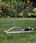 Metal Oscillating Sprinkler With Quick Connect Adapter Delivers Even Coverage For Lawns And Gardens Up To 3600 Sq Ft With 18 Brass Nozzles spraying water on a lawn.