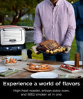 Woodfire Outdoor Pizza Oven 8 In 1 Portable Electric Roaster Heats Up To 700 Degrees Fahrenheit displayed on a patio table