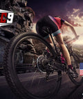 Cyclist riding on a mountain road at sunset, TAG9 logo, U.S. flag and Air Force emblem, scenic rocky landscape.