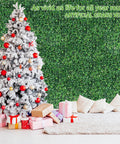 Snow-covered Christmas tree with presents in front of 24 Pack 20x20 Inches Artificial Boxwood Panels For Privacy Hedge Screen Outdoor Indoor Garden Fence Backyard Decor UV Protected Realistic Dense Leaves No See Through Privacy Solution wall.
