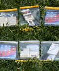 Yellow Large Waterproof Dry Bags 3 Pack Clear Pouches with Phone, Book, and iPad displayed on grass