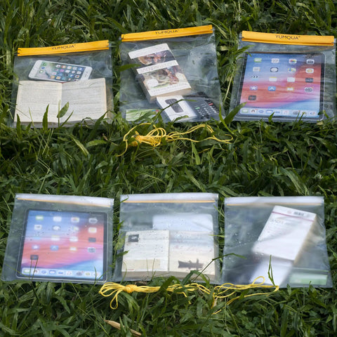 Yellow Large Waterproof Dry Bags 3 Pack Clear Pouches with Phone, Book, and iPad displayed on grass