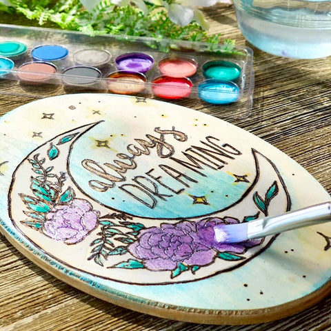 Starter Wood Burning Kit With Burner Pen, 5 Interchangeable Tips, 48-Piece Deluxe Pyrography Set, Stencils, Transfer Paper, Watercolor Paints And Brushes For Kids And Adults, showcasing a painted wooden plaque with floral design and text 'always dreaming'.