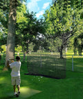 Golfer using Beefy 10x10ft Heavy Duty Golf Practice Net With High Impact Nylon Netting in a backyard setting.