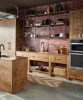 Rustic kitchen with a brick wall and wooden cabinets featuring a slick matte black deck mounted soap and lotion dispenser pump.