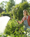 Woman using 29 Inch Sprayer Wand With Stainless Head For Easy Watering Of Hanging Baskets Plants Flowers Shrubs And Lawn UV protected