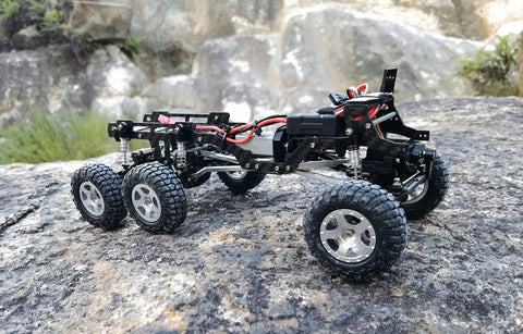 Dope LCG Carbon Fiber Chassis Frame For Axial SCX24 6x6 RC Crawler Upgrade on rocky terrain, highlighting lightweight frame and six wheels.
