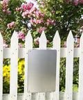 Blank metal tin sign on white fence with flowers, represents Metal Tin Sign 12 by 8 Inches Must Wear Personal Protective Equipment At All Times PPE Required for Workplace Safety Wall Decor for Shop Warehouse Factory.