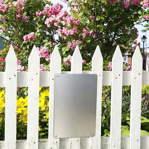 Blank metal tin sign on white fence with flowers, represents Metal Tin Sign 12 by 8 Inches Must Wear Personal Protective Equipment At All Times PPE Required for Workplace Safety Wall Decor for Shop Warehouse Factory.