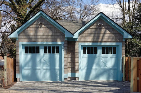 Two garage doors with blue trim, outdoor setting with trees in background, image displaying potential installation area for lighting.