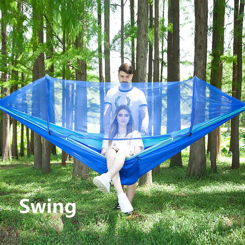 Couple sitting in Ultra Comfy Camping Hammock With Mosquito Net, 13ft Tree Straps And Carabiners, blue outdoor setup