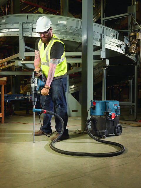 Worker using SDS Max Speed Clean Dust Extraction Bit for Vacuum Connected Drilling, enhancing anchor installations in industrial setting.