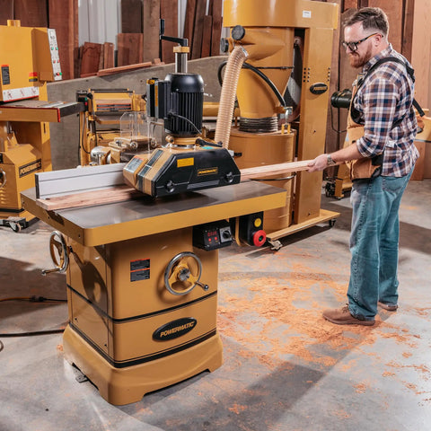 Solid As A Rock Three Roll Power Feeder With Heavy Duty Gear Driven Chain System And One Horsepower Motor For No Sweat Feed Control Right On The Workbench, a user operating the feeder at a workbench.