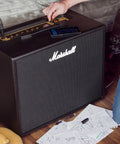 Code50 Digital Guitar Amplifier With Fifty Watt Output One Hundred Plus Presets Twenty Four Digital Effects Fourteen Preamp Models Bluetooth Connectivity Three Point Five Millimeter Aux Input Versatile Tone For Practice Rehearsal And Live on a wooden floor with papers and a guitar nearby