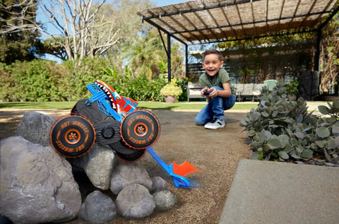 Child playing with Monster Trucks Remote Control Tiger Shark Climber RC Vehicle With Grip Action Tires climbing over rocks.
