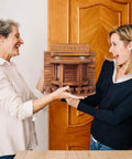 Two people holding a Crescent Wooden Squirrel Feeder Table for outdoor use, showcasing the picnic table style and sturdy structure.
