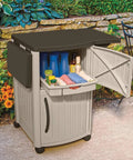 Outdoor Grilling Prep Station With Storage Portable Backyard Kitchen Counter Durable Resin Weather Resistant Top Cabinet For Serving Tray And More With Drop Leaf Extensions Taupe Brown, with cabinet open showing contents, set in garden area.