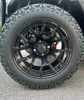 Close-up of black alloy wheel and tire of White 6 Passenger 4+2 Seater Electric Golf Cart With 48V 150Ah Lithium Battery And One Click Start.