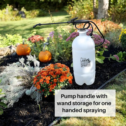 Two Gallon Lawn And Garden Sprayer With 34 Inch Anti Kink Hose placed in a garden bed with flowers and pumpkins.