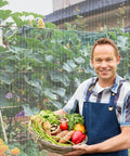Gardener holding basket of vegetables in front of Fortify Your Garden With A 4 By 10 Foot Plant Netting Pest Barrier that fends off invaders.