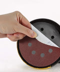 Five Inch 8 Hole Sanding Discs Set, 30 Pack with Assorted Grits 40 80 120 220 320 600 being peeled off sander
