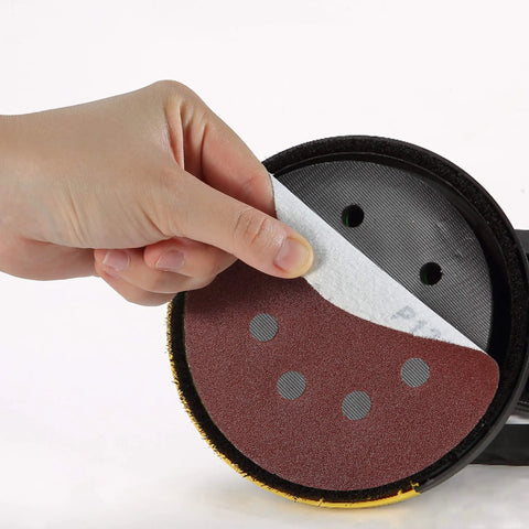 Five Inch 8 Hole Sanding Discs Set, 30 Pack with Assorted Grits 40 80 120 220 320 600 being peeled off sander
