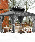 Built Tough 10 Foot By 12 Foot Aluminum Hardtop Gazebo With Double Metal Roof And All Weather Permanent Outdoor Canopy With Netting And Curtains For Patio, Backyard, Deck Or Lawn, installed in snowy backyard with furniture visible.
