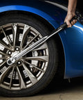 Half Inch Drive Click Torque Wrench 25-250 Ft-Lb Range being used on a car wheel, shows Cr-V ratchet head and non-slip knurled grip.