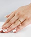 Real Deal 0.15 Ctw Genuine Round Cut Diamond Wedding Band Encased In Solid 14K Yellow Gold Machine Set worn on hand with manicured nails.