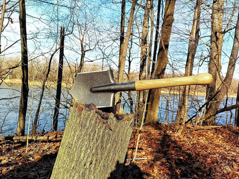 Battle Wolf Military Grade Survival Shovel with carbon steel head and hardwood handle stuck in tree stump