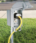 Tough As Nails One Gang Weatherproof In Use Outlet Cover With Fo Sho Quick Fit Keyhole Mount For Exterior Walls Extra Duty Rated Gray Housing tight seal against storms, showing outdoor use with a yellow cord.