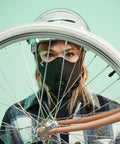 Person wearing Road Ready Nano Light Hexagon Motorcycle Half Face Mask With Anti Pollution Filter under a helmet, holding bicycle wheel.