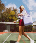 Woman carrying Lilac Breeze 11 Qt Tag-Along Cooler With Strapped Crossbody Carry, Leakproof Lid Locks, on a tennis court