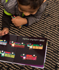 Child reading Totally Rad Toddler Counting Book Featuring Ten Noisy Rickshaws And Hella Fun Indian Culture educational material with colorful trucks.