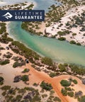Aerial view of vehicles on sandy trail beside turquoise river, showcasing natural landscape for rugged adventures, lifetime guarantee badge.