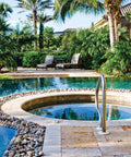 Front view of outdoor pool with circular spa, stone deck, pebble border, and stainless steel handrail