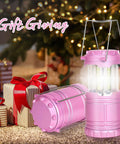 Pink LED Camping Lanterns with Portable Handle next to gift boxes under a decorated Christmas tree, lit with warm glow