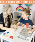 Cool Math Posters For Elementary Classrooms With Multiplication Chart And Place Value Chart Laminated 11x17 Wall Decor Set Of 12 Greenery Themed Math Bulletin Board Essentials That Make Learning Fun with teacher helping student.