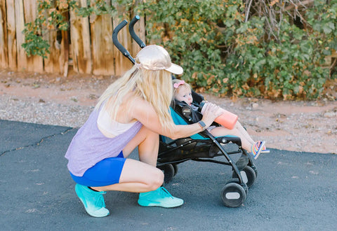 Woman kneeling next to baby in stroller holding insulated leak proof straw lid for Summit and Hydro Flask wide mouth bottles road trip ready