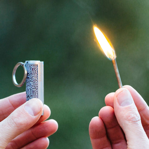 Relightable Permanent Fire Starter Metal Kit 2 Pack, waterproof emergency keychain lighter striker igniting flame outdoors.
