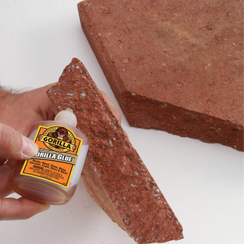 Applying Heavy Duty Waterproof Polyurethane Glue For Wood, Metal, Stone, Ceramic, Glass, And Concrete, 2 Ounce Brown Bottle on brick