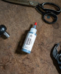 Powdered Graphite Lubricant 1.13 oz bottle on workbench with metal tools, for smooth sliding of locks, reels, and metal surfaces.