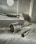 3 9/16 Inch Rotary Hammer Core Bit Set With Wave Design Delivers Cleaner Holes Up To 6 Inches Carbide Tipped Centering Bit Asymmetrical Carbide Teeth For Faster Cutting And Longer Life All In One Core Delivers Power Direct To Bit End shown on concrete surface