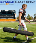 Man carrying a portable 6x6ft Football Throwing Net With Five Target Pockets in a black carry bag on a football field