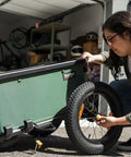 Person attaching Two 16 By 3 Inch Bike Trailer Wheel Kit With Aluminum Rim And Hub, Steel Spokes, Knobby Tread to a trailer