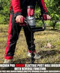Person using 1500W Electric Post Hole Digger With 6 Inch And 4 Inch Augers, Reverse Function, Carry Bag in a garden.
