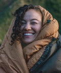 Person smiling while wrapped in a 0 Degree Sleeping Bag For All Weather Camping Cozy And Warm With Roomy Half Circle Mummy Hood.