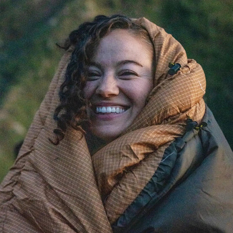 Person smiling while wrapped in a 0 Degree Sleeping Bag For All Weather Camping Cozy And Warm With Roomy Half Circle Mummy Hood.